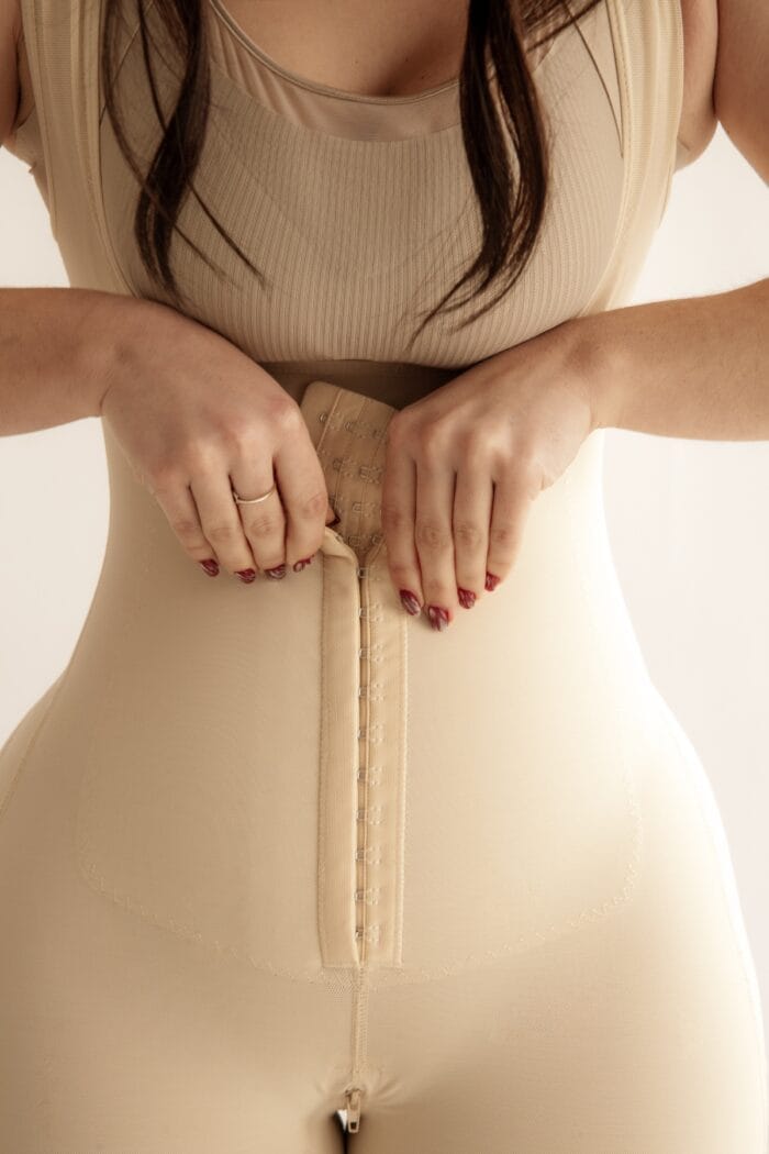 Detalle frontal de faja reductora beige con cierre de broches en el abdomen